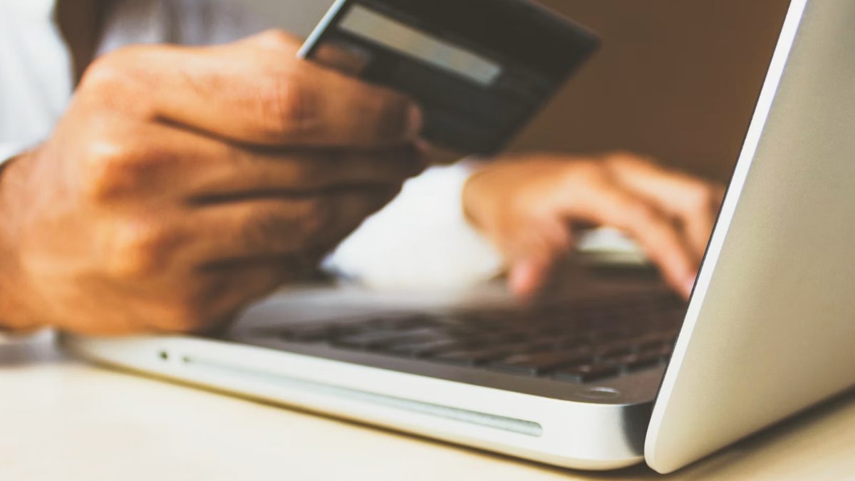 Person holding a credit card while shopping online on a laptop